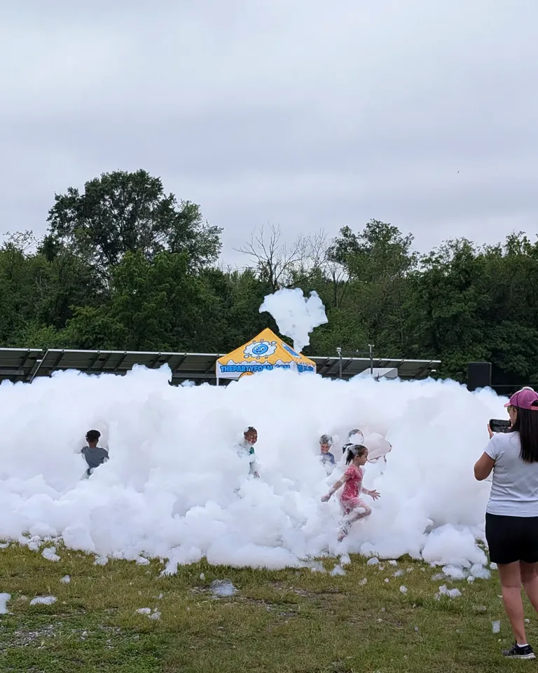 Group of kids playing in a large foam cloud at a school field day