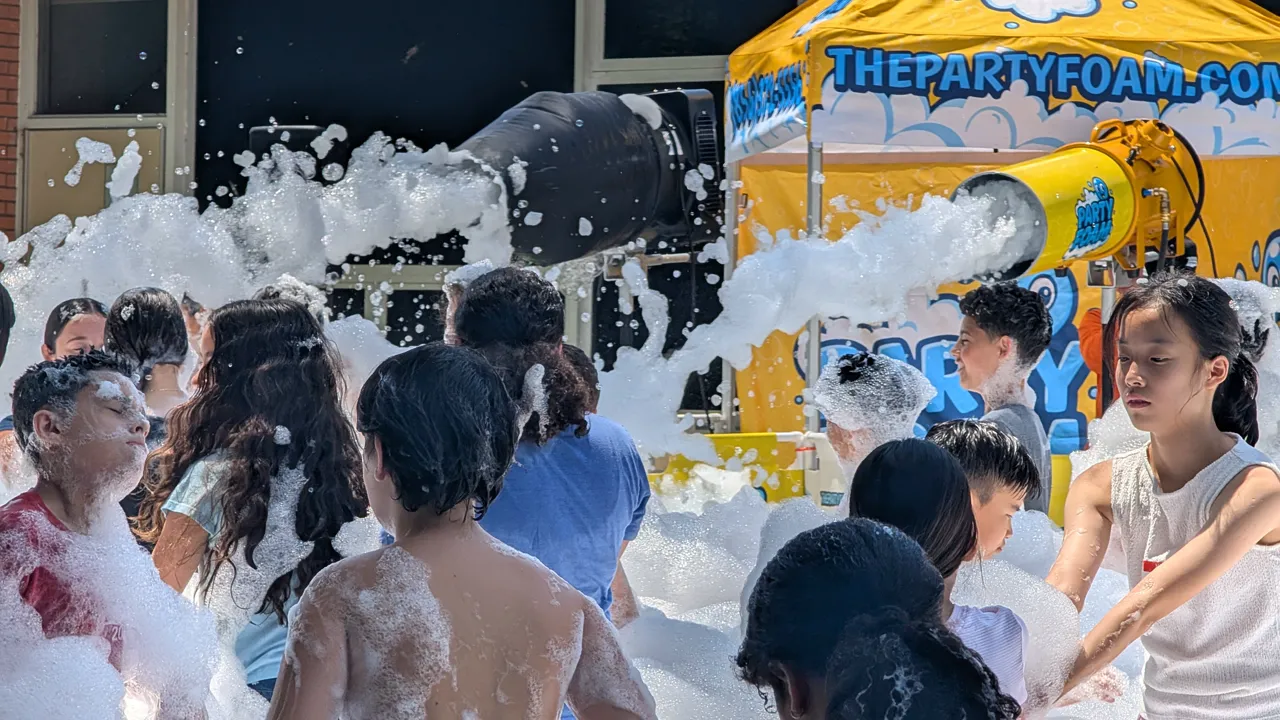 kids playing in foam beside the branded Party Foam tent and cannon at a sunny South Jersey summer event